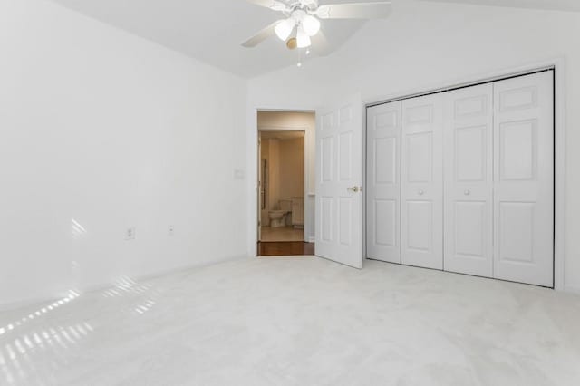 unfurnished bedroom with vaulted ceiling, carpet flooring, a closet, and ceiling fan