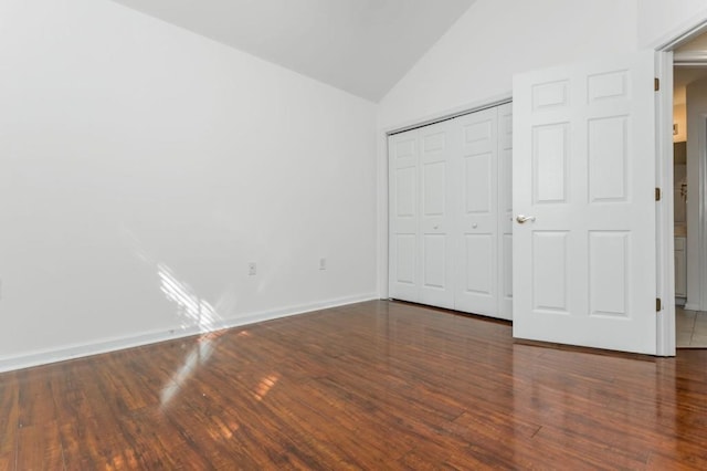 unfurnished bedroom with baseboards, lofted ceiling, a closet, and wood finished floors