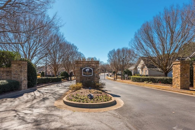 view of street with curbs, a gated entry, and a gate