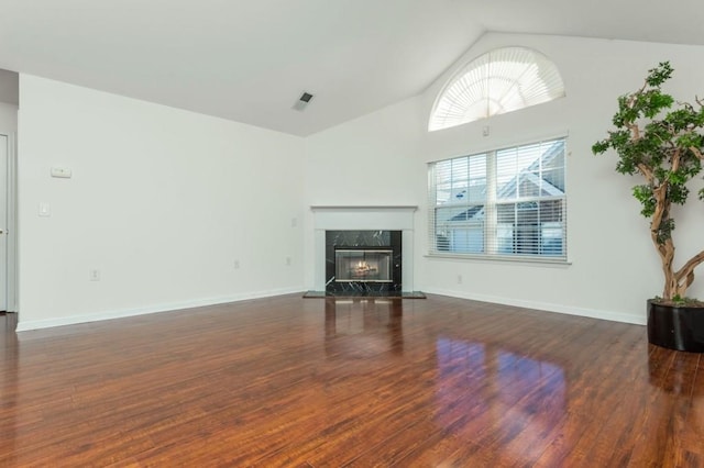 unfurnished living room with wood finished floors, a fireplace, baseboards, and high vaulted ceiling