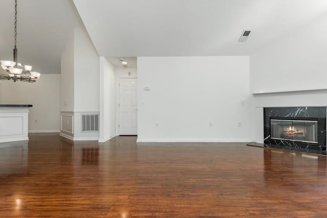 unfurnished living room featuring wood finished floors, visible vents, and a high end fireplace