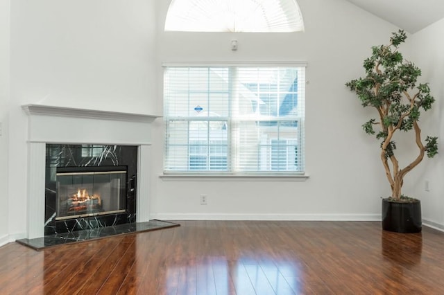 living area with baseboards, wood finished floors, lofted ceiling, and a premium fireplace