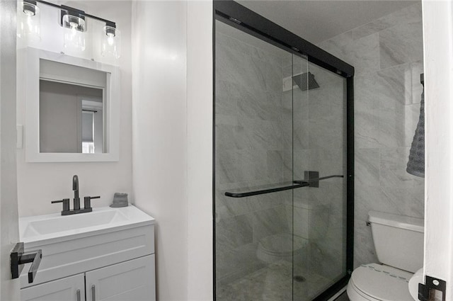 bathroom featuring vanity, toilet, and a shower with shower door