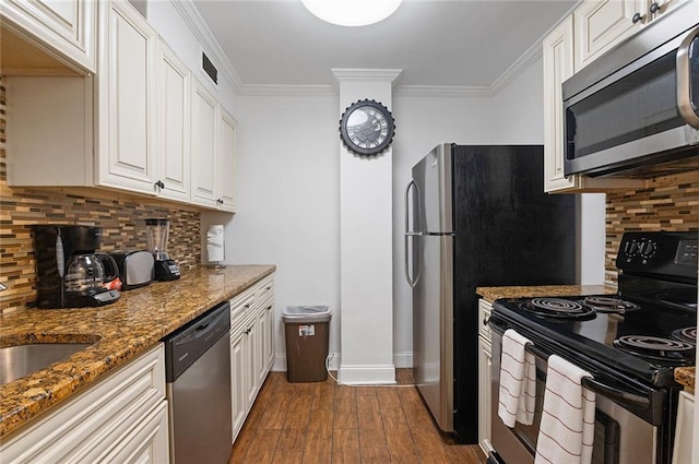 kitchen featuring appliances with stainless steel finishes, dark stone countertops, wood-type flooring, ornamental molding, and white cabinets