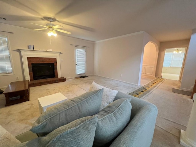 living room featuring light carpet, ornamental molding, a brick fireplace, and ceiling fan