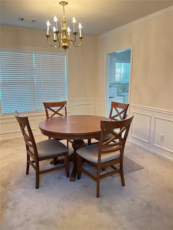dining space featuring crown molding, light colored carpet, visible vents, an inviting chandelier, and a decorative wall