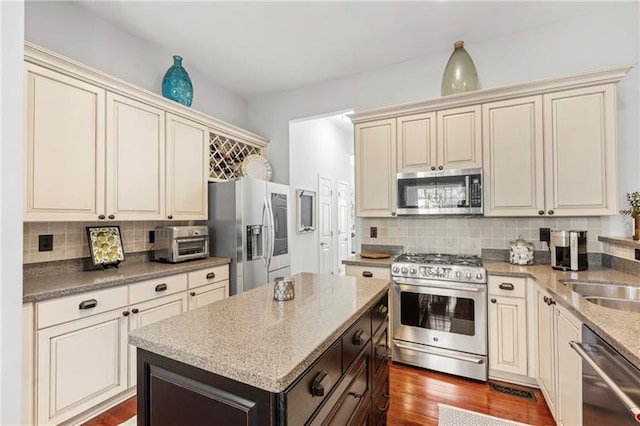 kitchen featuring stainless steel appliances, cream cabinets, and tasteful backsplash