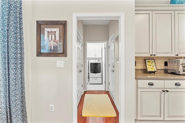 corridor with washer / clothes dryer, wood finished floors, and baseboards