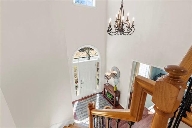 foyer entrance featuring a high ceiling, a chandelier, plenty of natural light, and wood finished floors