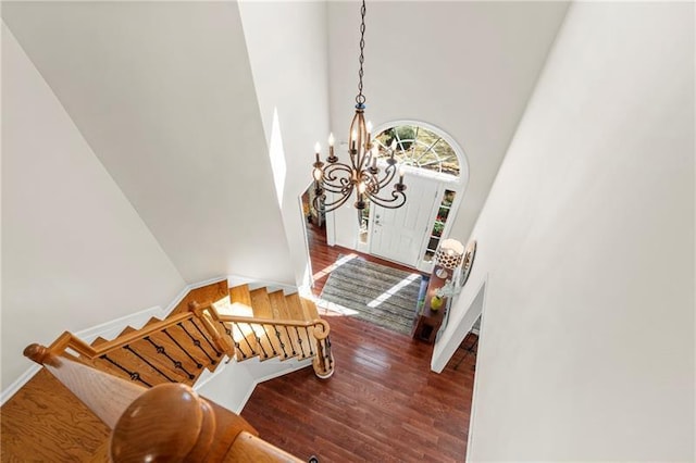 staircase featuring a chandelier, wood finished floors, and a high ceiling
