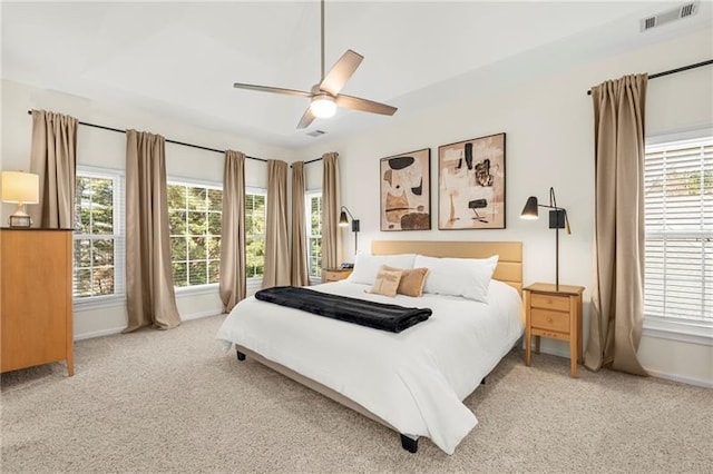bedroom with multiple windows, light colored carpet, and baseboards