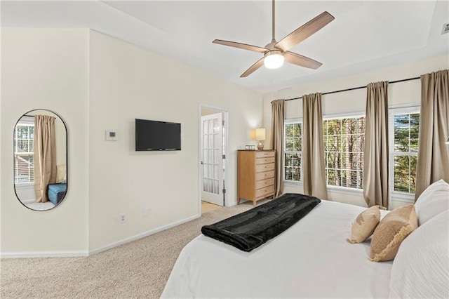bedroom with light colored carpet, baseboards, multiple windows, and a ceiling fan