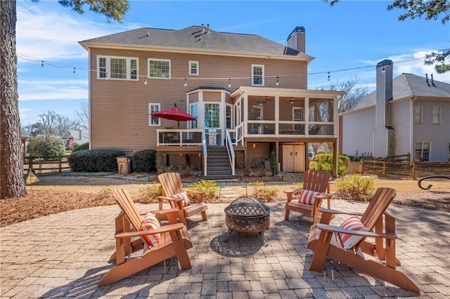 rear view of property featuring a fire pit, a sunroom, a patio, stairs, and fence