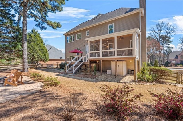 back of property featuring a sunroom, stairs, a chimney, ceiling fan, and fence