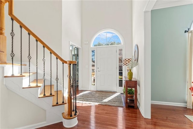 entryway featuring wood-type flooring, stairs, a high ceiling, and baseboards