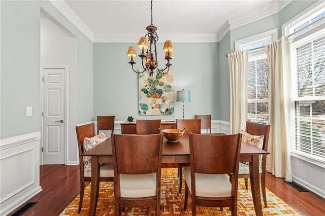 dining space featuring a chandelier, wood finished floors, and ornamental molding