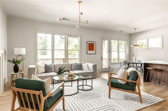 living room with a chandelier, crown molding, and light hardwood / wood-style flooring