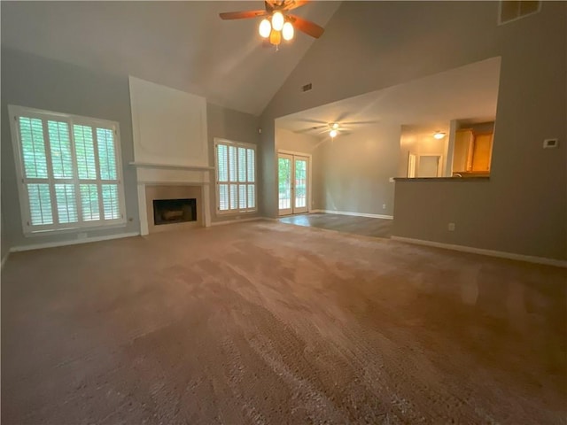 unfurnished living room with high vaulted ceiling, ceiling fan, and carpet