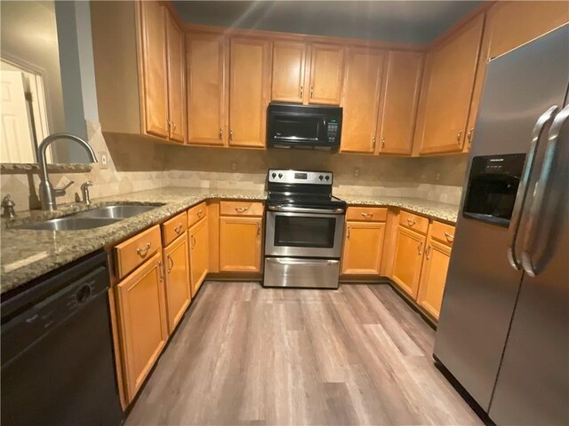 kitchen with light stone countertops, sink, light wood-type flooring, and black appliances