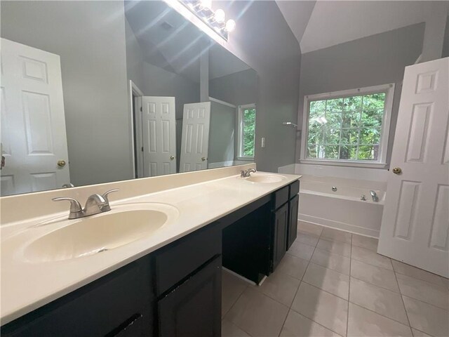 bathroom featuring tile patterned floors, vaulted ceiling, vanity, and a bathtub