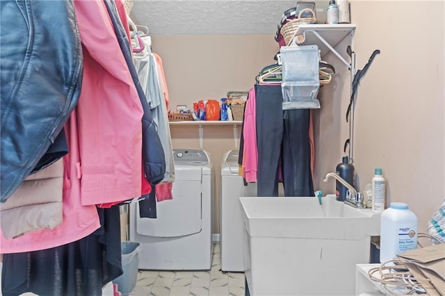 clothes washing area featuring a sink, marble finish floor, laundry area, a textured ceiling, and washing machine and dryer