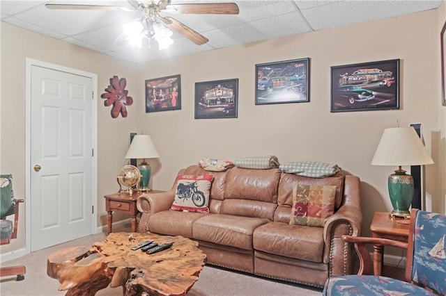 living area featuring carpet flooring, a ceiling fan, and a drop ceiling
