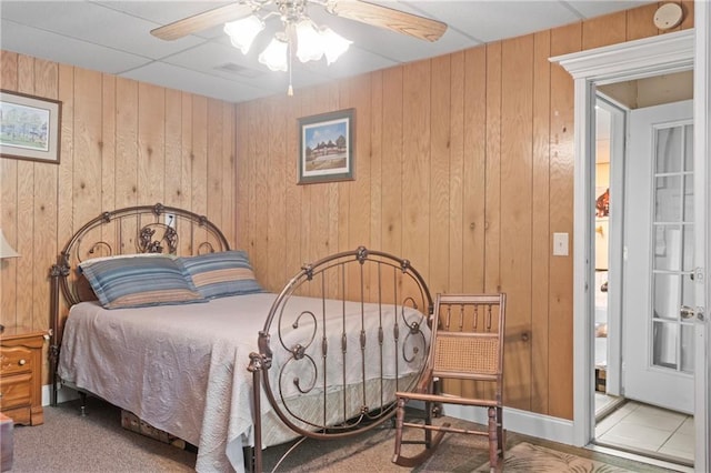 bedroom with ceiling fan and wood walls