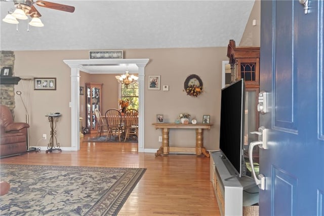 entryway with light wood finished floors, a textured ceiling, baseboards, and ceiling fan with notable chandelier