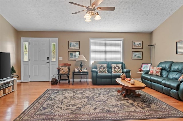 living room with a textured ceiling, wood finished floors, a ceiling fan, and a healthy amount of sunlight