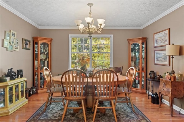 dining area featuring ornamental molding, light wood-style floors, an inviting chandelier, and a textured ceiling