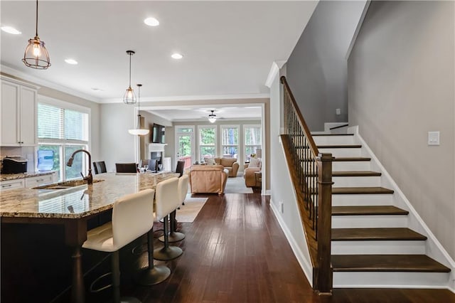 3920 Baverton Dr, Suwanee, GA 30024 - kitchen with a sink, ceiling fan, light stone countertops, white cabinetry, and decorative light fixtures