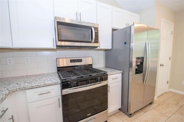 kitchen with light stone counters, white cabinets, light tile patterned flooring, stainless steel appliances, and decorative backsplash