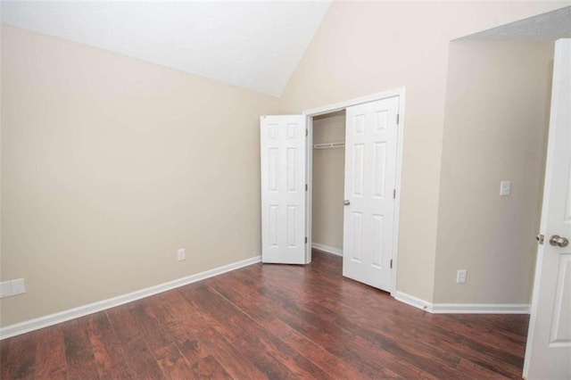 unfurnished bedroom with a closet, lofted ceiling, and dark wood-type flooring