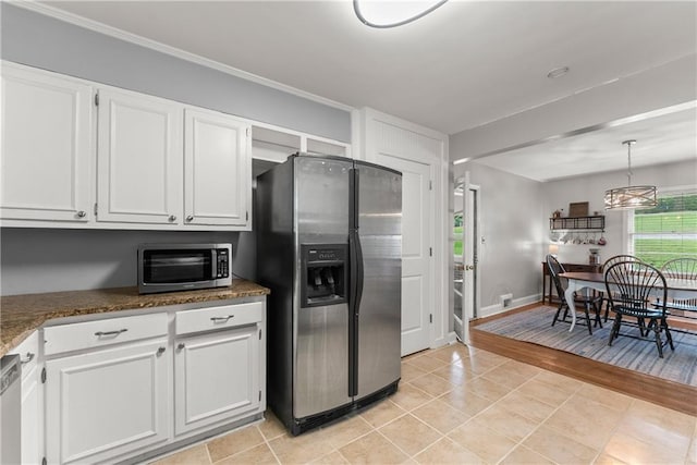 kitchen with appliances with stainless steel finishes, white cabinets, light tile patterned floors, hanging light fixtures, and baseboards