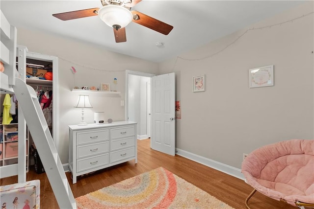 bedroom featuring wood finished floors, baseboards, a closet, and a ceiling fan
