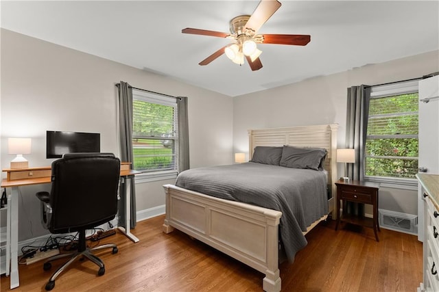 bedroom featuring wood finished floors, a desk, a ceiling fan, and baseboards