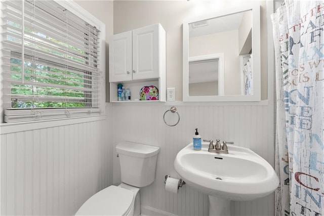 bathroom featuring wainscoting, toilet, and a sink