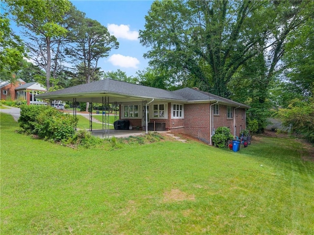 back of property with a carport, a lawn, brick siding, and a patio area