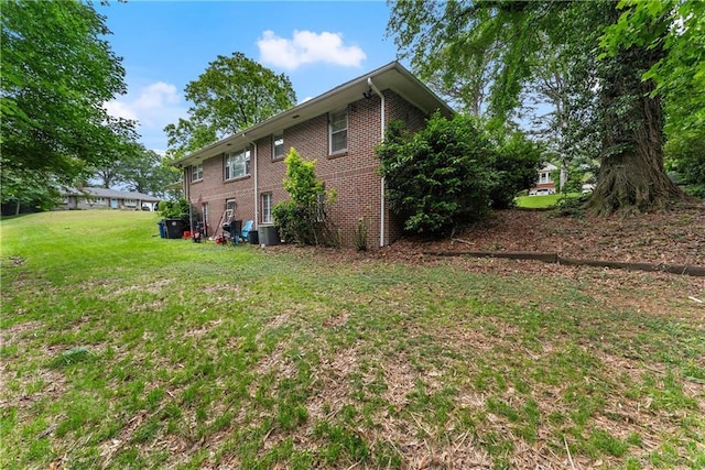 rear view of house featuring brick siding and a yard