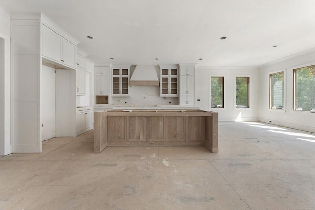 kitchen featuring premium range hood, a kitchen island, white cabinets, and glass insert cabinets