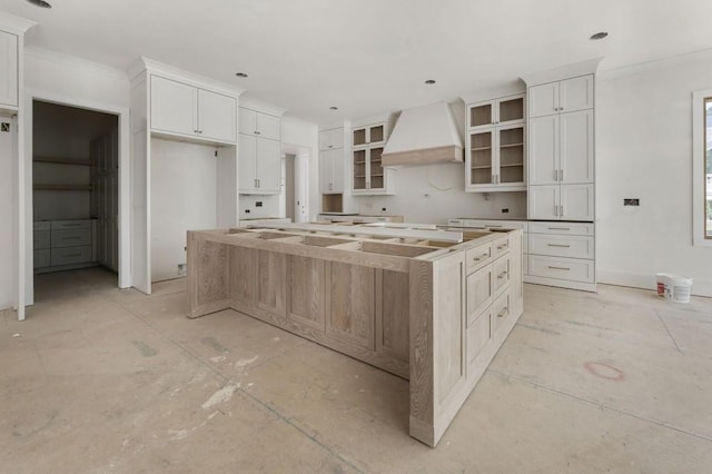 kitchen with custom exhaust hood, a large island, glass insert cabinets, white cabinets, and recessed lighting