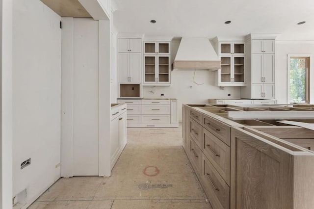 kitchen featuring custom exhaust hood, glass insert cabinets, and white cabinets