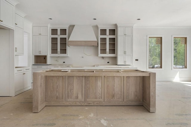 kitchen featuring custom range hood, a center island, glass insert cabinets, and white cabinetry