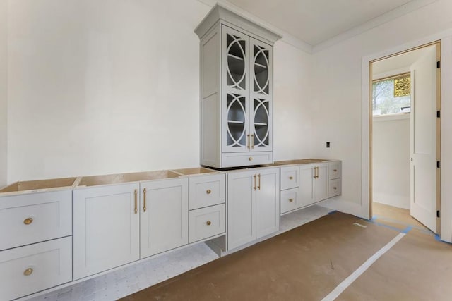 interior space with crown molding, baseboards, and glass insert cabinets