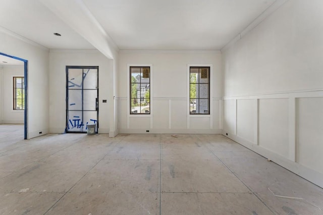 empty room with a wainscoted wall, ornamental molding, and a decorative wall