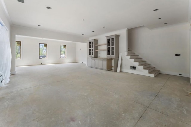 unfurnished living room featuring stairway and concrete floors