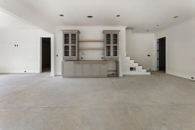 spare room with crown molding, stairs, and concrete floors