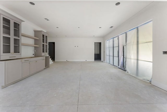 unfurnished living room with concrete flooring and baseboards