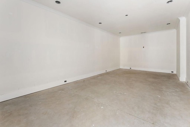 spare room featuring concrete flooring, crown molding, and baseboards