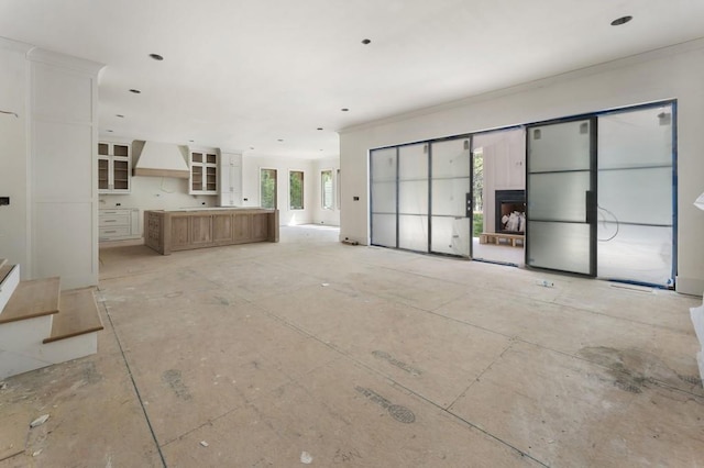 unfurnished living room featuring ornamental molding and stairway